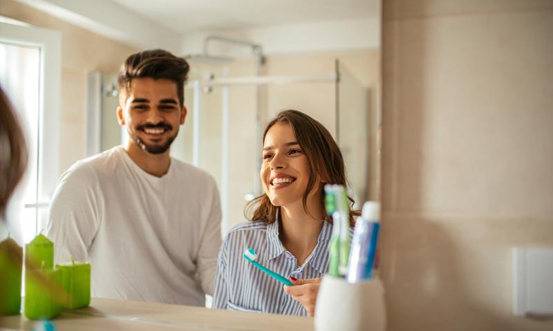 Young Couple In Bathroom Brushing Teeth