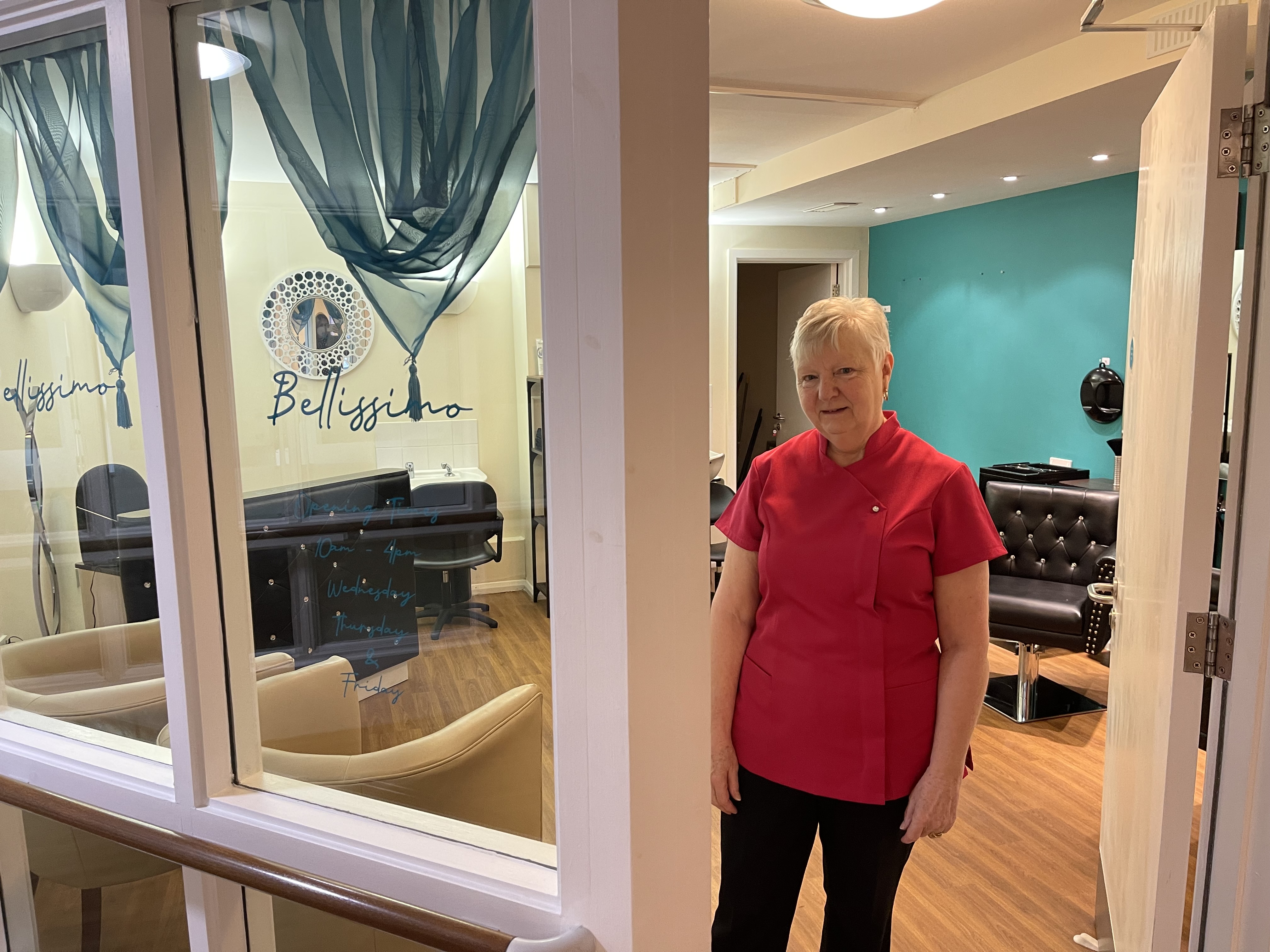 Pat standing next to the revamped salon and new sign