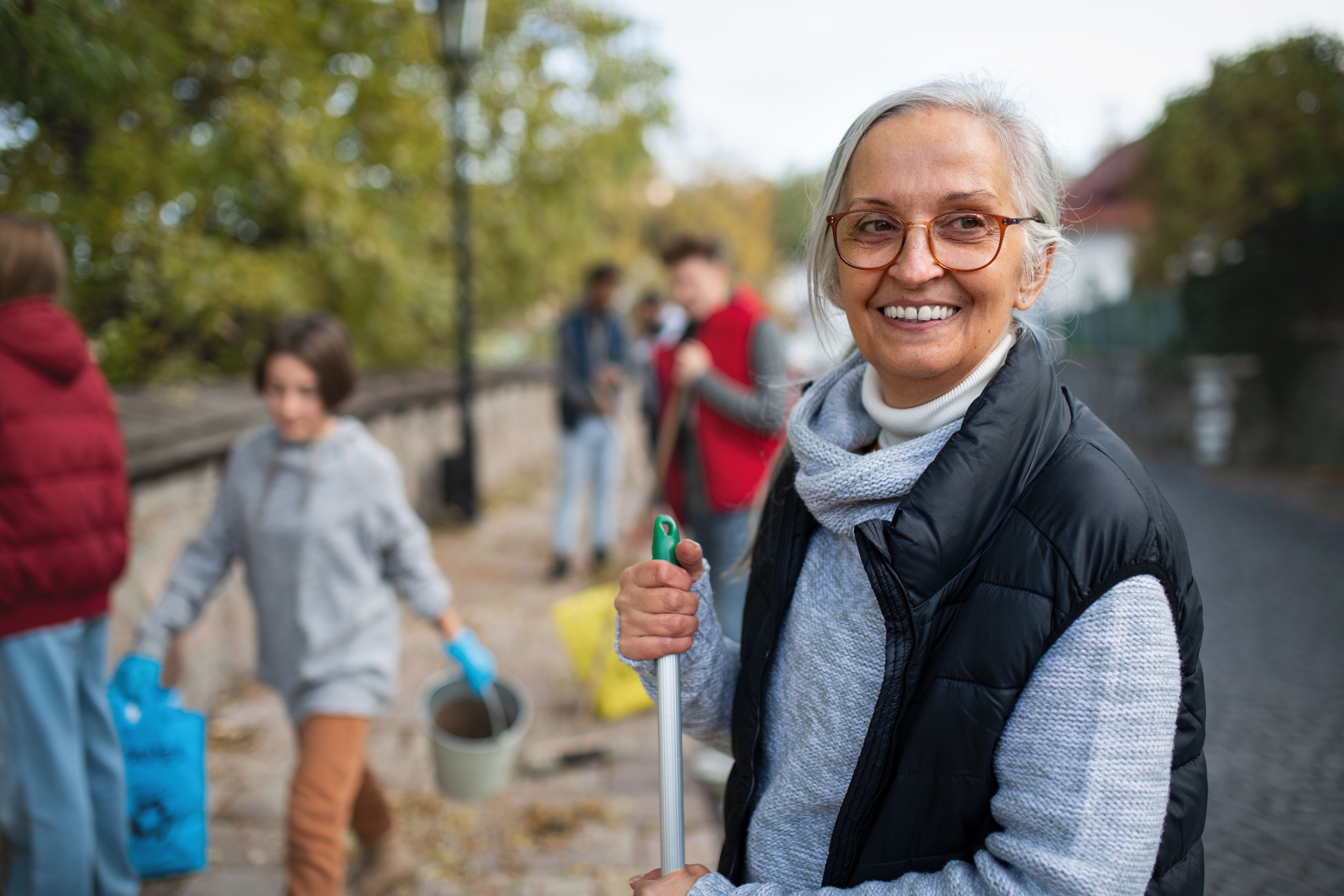 Woman with a group of community workers clearing leaves and litter picking