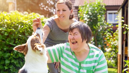 Older Mother And Daughter In Garden With Dog