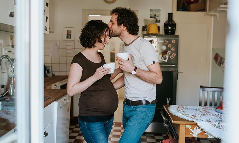 Pregnant Couple Drinking Tea In The Kitchen