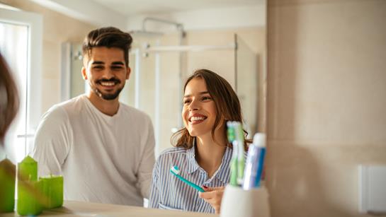 Young Couple In Bathroom Brushing Teeth