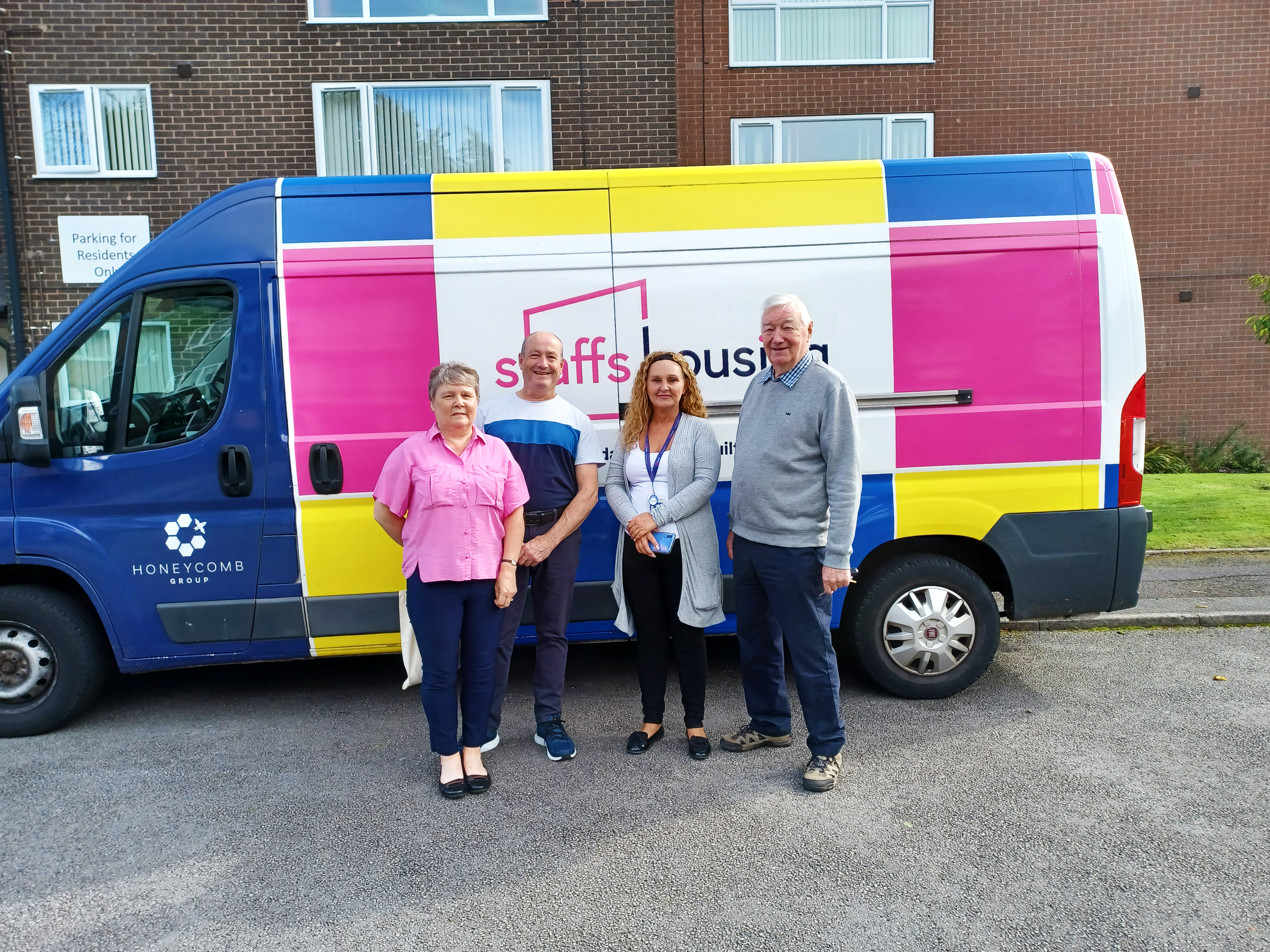 Housing officer and residents standing in front of a Staffs Housing branded van at a scheme.